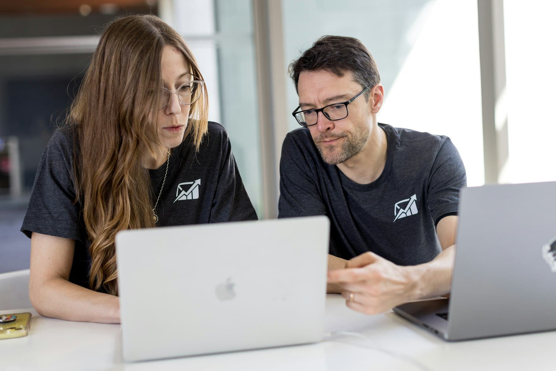 Zwei Kollegen arbeiten an ihren Laptops gemeinsam einen Plan durch